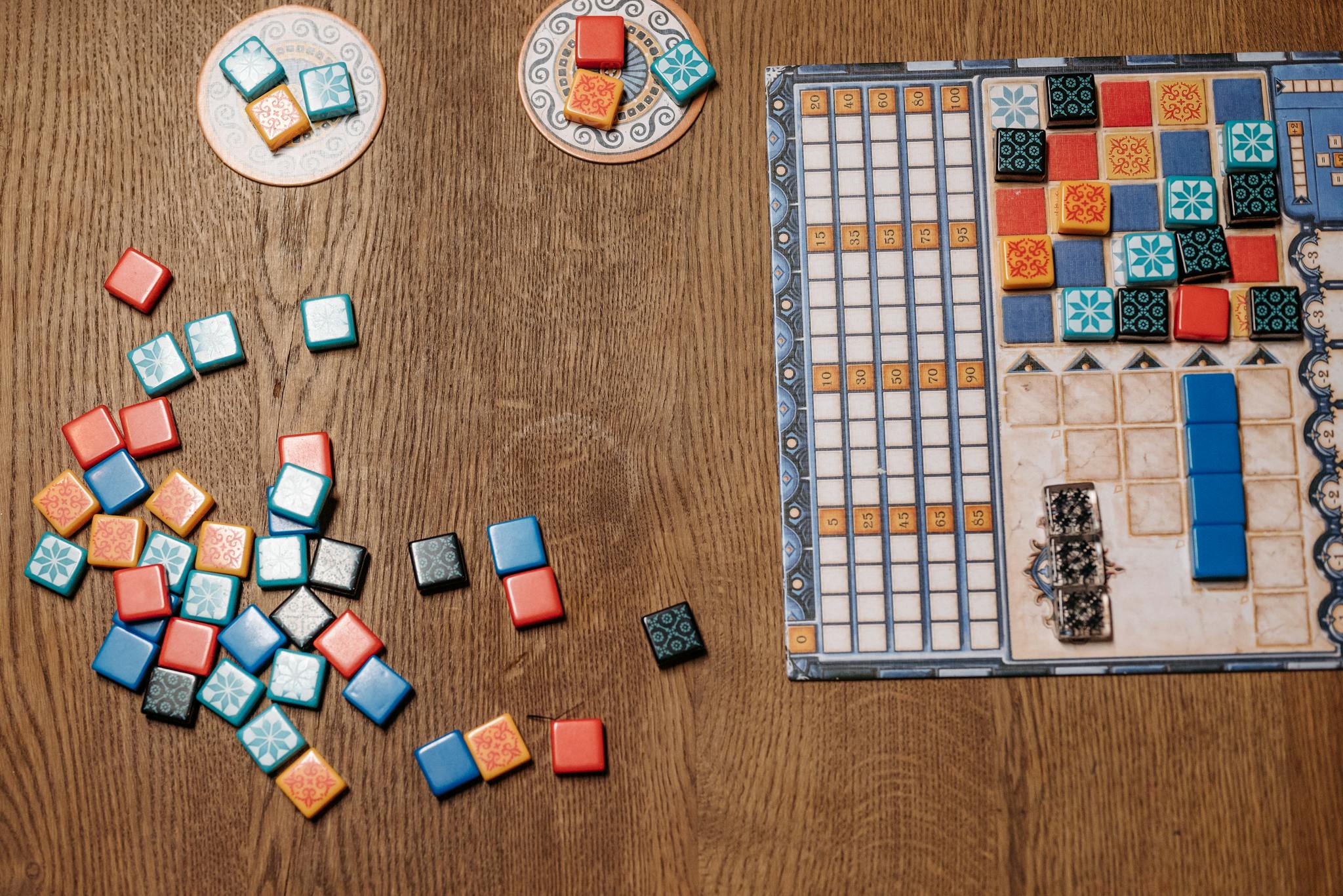 Top view of a strategy board game with colorful tiles and game board on a wooden table.